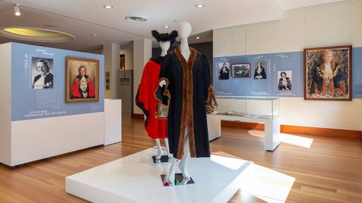 View of Tracing Her Steps installation in a gallery space with two mannequins in mayoral robes in the foreground