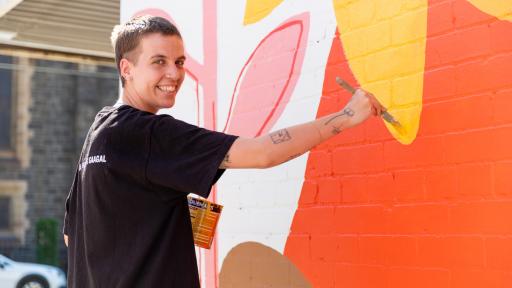 Artist Abbey Rich painting the mural and smiling at the camera.