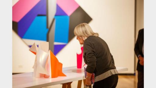 Visitor to 'Light Gestures' looking at a sculpture on a table.