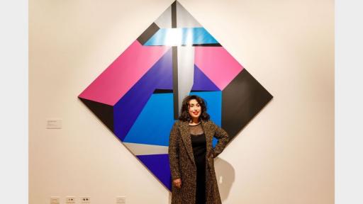 Portrait of artist Samara Adamson-Pinczewski in front of one of her abstract geometric paintings.