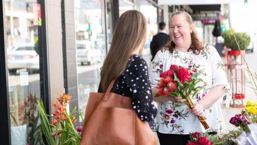 Two women chat to each other outside a florist