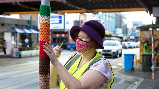 A woman yarn bombing on Glenferrie Road