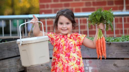 A young girl with carrots and a FOGO caddy