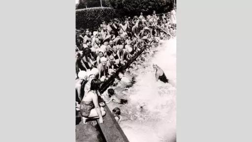 A large group of children at a swimming lesson.