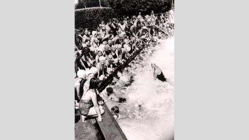 A large group of children at a swimming lesson.