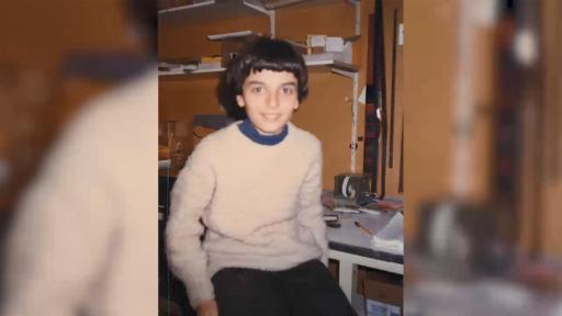 A still from a 1981 video of a young boy sitting at a desk
