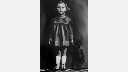 A small girl standing and holding the hand of a teddy bear whose feet are on the ground