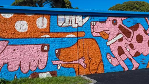 a building wall painted with images of dogs sitting and playing