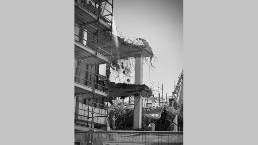 Photo by Ro Allen of a multi story building that is torn down to it's concrete frame with scaffolding and demolition equipment around it