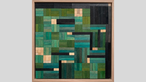 A framed piece of art made out of wooden rectangles that a range of greens to dark blue/greay colours, and are arranged in square patterns of different sizes
