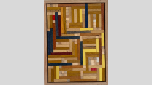 A framed piece of art made of wooden rectanges arranged to tesselate with each other changign from horizontal to vertical throughout, and using mostly light brown pieces along with some yellow and blue and a few red