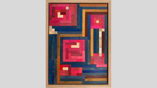 A framed piece of art made of wooden rectanges arranged pink squares of varying sizes with mostly blue blocks between the squares