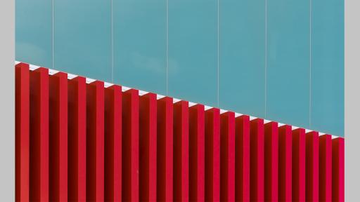 Photo by Ian Spence of the architectural detail on a building featuring red square columns and a blue wall above
