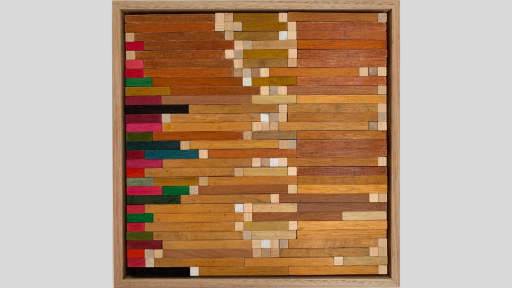 A framed piece of art made up of wooden blocks arranged horizontally progressing from rainbow colours on one side to a range of light browns