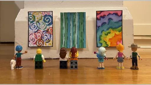 Photo by James Ding of lego people looking at 3 proportinately sized artworks on a wall at ground level