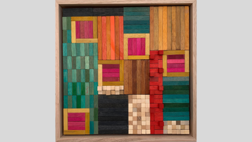 A framed piece of art made up of wooden rectangles arranged in squares and columns throughout the piece, using bright colours and some raised pieces that emerge from the artwork
