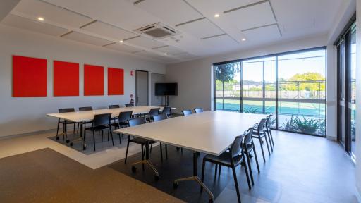 A meeting room with a window looking onto a tennis court