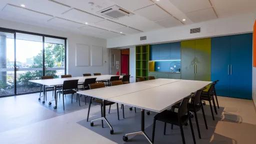 A meeting room with large tables and a small kitchen
