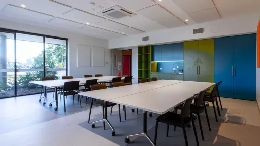 A meeting room with large tables and a small kitchen