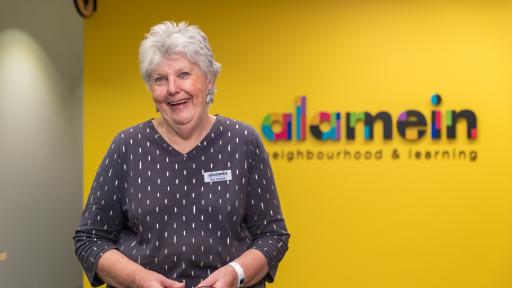 A volunteer standing in from of the Alamein Neighbourhood and Learning Centre sign