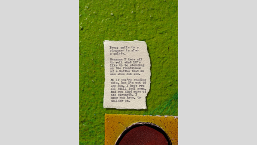 A piece of torn paper with a poem printed from a typewriter, sitting on a green textured surface with a brownish yellow tile below the paper