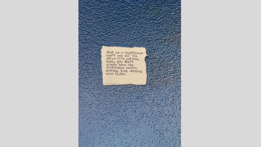 A piece of torn paper with a poem printed from a typewriter, sitting on a blue shiny textured surface