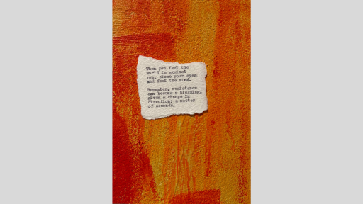 A piece of torn paper with a poem printed from a typewriter, sitting on an orange and red textured surface