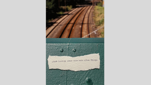 A piece of torn paper with a short piece of text printed from a typewriter, sitting on the site of a fence overlooking a traintrck that goes underneath the fence