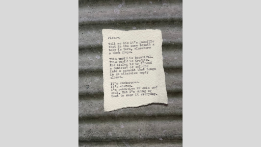 A piece of torn paper with a short piece of text printed from a typewriter, sitting on a grey piece of corregated iron roofing