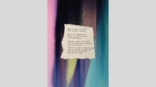 A piece of torn paper with a poem printed from a typewriter, sitting on a multicoloured rainbow surface