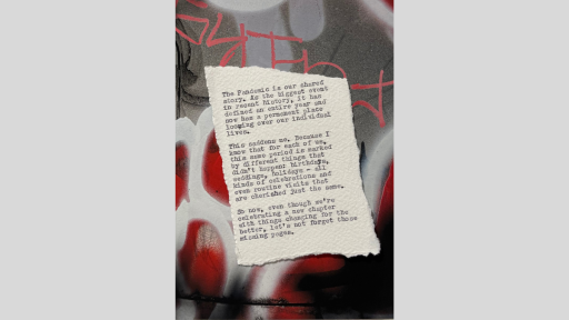 A piece of torn paper with a short piece of text printed from a typewriter, sitting on a graffitied surface with grey, white and red graffiti paint across the backdrop