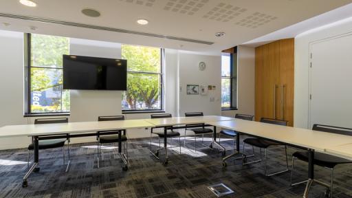 A carpeted meeting room with a TV screen and windows