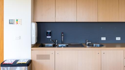 A neat kitchenette with rubbish and recycling bins