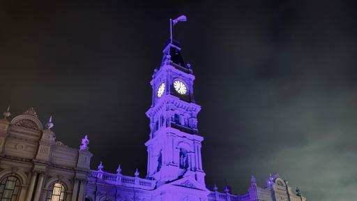 The Hawthorn Arts Centre building's clock tower lit up with a purple light