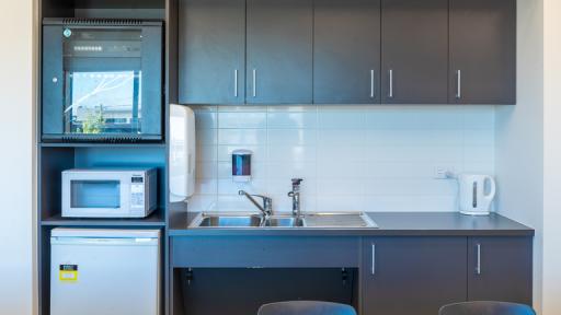 A tidy kitchenette with sink, bench space and microwave