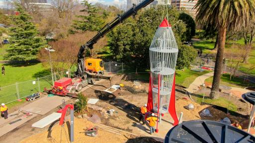 A large crane placing the a large rocket in a park
