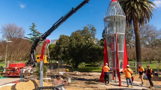 People standing around a big rocket and crane in a park