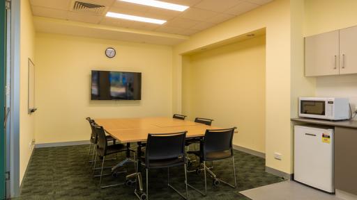 A small meeting room with TV and kitchenette