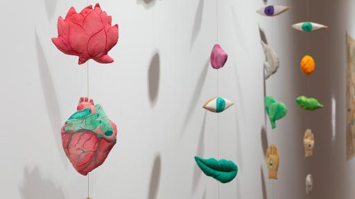 hanging mobile sculpture of body parts and leaves made of fabric