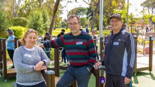 Three people standing together, amongst the new exercise equiptment at the seniors exercise park