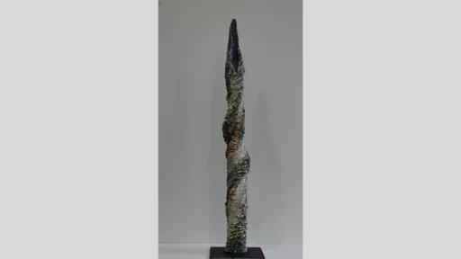Tall, twisted vertical sculpture with highly textured surface