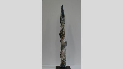Tall, twisted vertical sculpture with highly textured surface