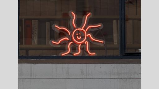 A led light in the shape of a hand-drawn sun with a smiley face