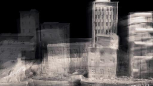 Blurry black and white image of tall buildings that look to be made of clay