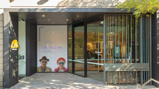 Entrance to Light Sensitive art installation, with glass doors and a photo of two elderly people wearing sunglasses.