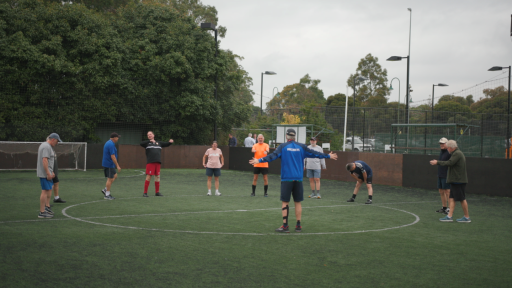 A group of people playing walking football together on a soccer pitch