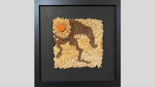 An artwork made of layered pieces of coloured wood that are arranged to flow out from the top right orner which has a rick on it and looks like a sun, with darker wood rays coming out from this