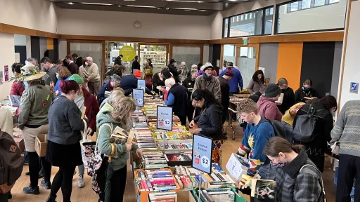 People rummage through boxes of used books on trestle tables