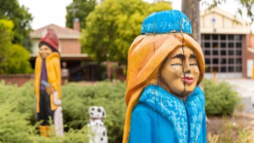 2 painted, life-size wooden sculptures in a garden