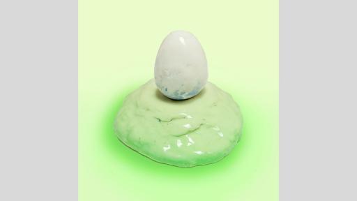 Ceramic sculpture of a white egg on a light green mound. 